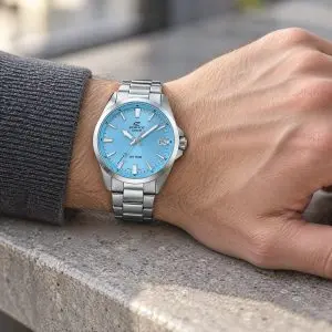 Casio Edifice karóra világoskék számlappal és acél karkötővel, férfi csuklón, kőpárkány előtt